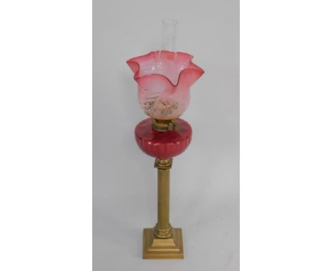 A Sherwoods Ltd late 19thC brass oil lamp, of fluted column form, with a faceted ruby glass reservoir and a frosted cranberry