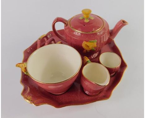 A Royal Winton early 20thC pottery solitaire breakfast set, moulded with flowers against a powder red ground, comprising teap