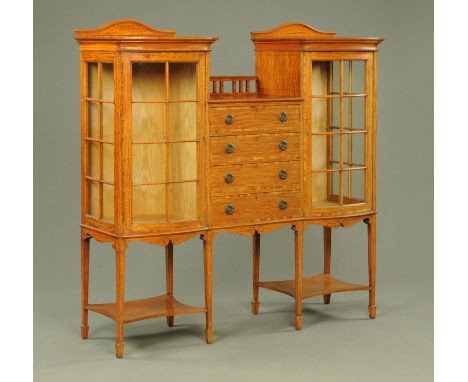 An Edwardian satinwood display cabinet, with drop centre and four drawers flanked on either side by a glazed cupboard and all