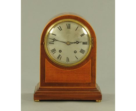 An Edwardian mahogany and boxwood strung mantle clock, having an arched top and a silvered dial with Roman numerals and two-t