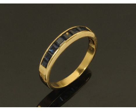 A Continental 18 ct gold ring, set with a band of square sapphires, size L/M. CONDITION REPORT: The ring is in good structura