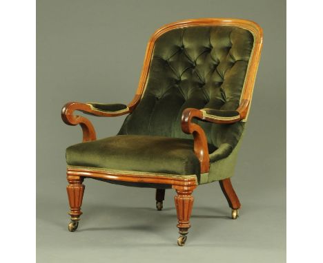 An early Victorian framed easy chair, upholstered in green material with button back and sprung seat and with reeded tapering