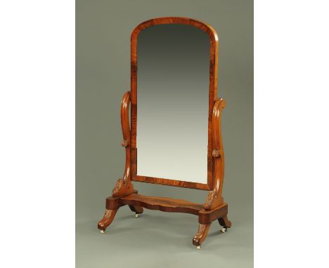 A Victorian mahogany cheval mirror, with arched top supported on foliate carved scroll supports united by a shaped stretcher 