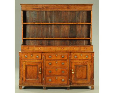 A George III oak dresser, with six short spice drawers above a breakfront base with a series of drawers and two panelled cupb