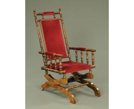 A 19th century American rocking chair, the turned frame with upholstered head rest, back, arm rest and seat, on a shaped base