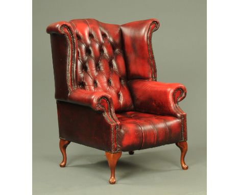 A Georgian style oxblood leather button back wing armchair, 20th century, supported on four cabriole legs.  Width 87 cm, heig