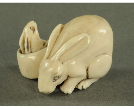 An amusing Japanese ivory netsuke, late Meiji/early Taisho period, the adult rabbit in crouching position next to a pot from 