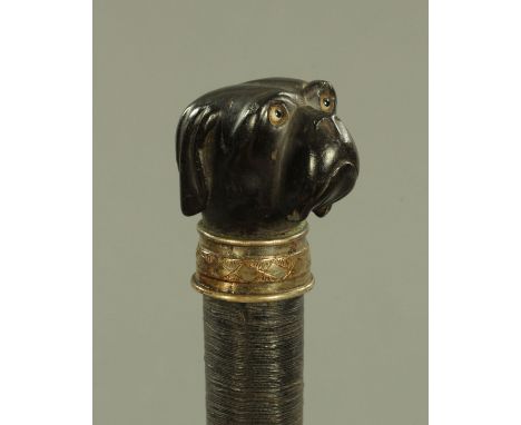 A 19th century carved ebony and thread bound walking cane, the carved ebony grip in the form of a dog with inset coloured gla