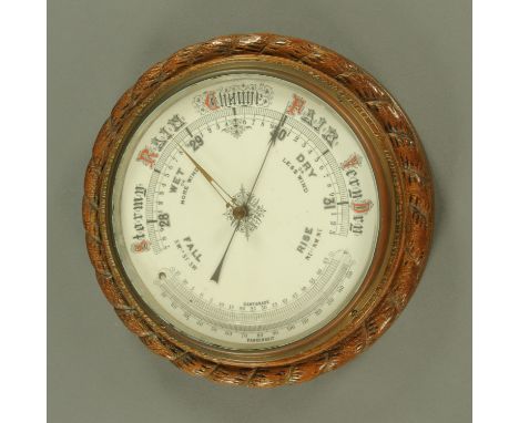 A late Victorian carved oak wall mounted barometer, with ceramic dial in a carved rope twist frame.  Diameter 34 cm. 