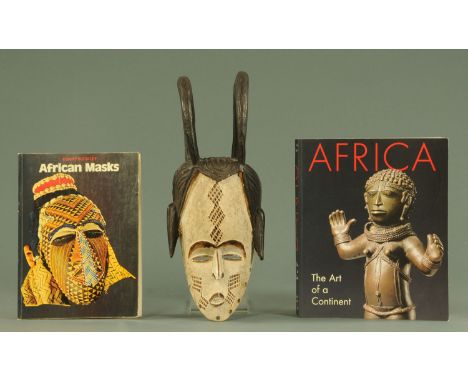 A West African carved wood mask, 20th century, Nigerian/Cameroon, with stylised headdress and scarification marks to the face