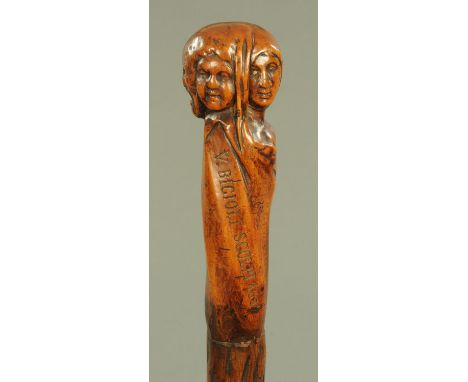 A 19th century European carved wood walking stick, the grip carved with four faces to include a lady and a bearded man and si