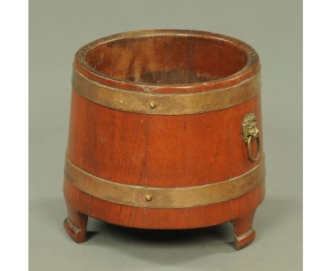 An early 20th century coopered planter, with copper bindings, brass lion paw and ring handles and all on three short feet.  W