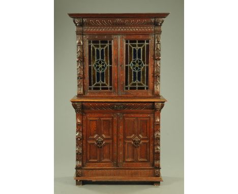A late Victorian Flemish carved oak bookcase on cupboard, late 19th century, with lion mask and foliate carving flanking colo