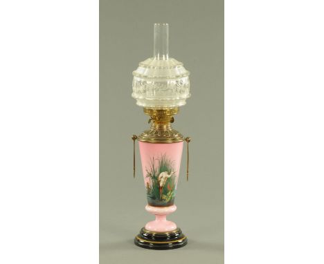 A Victorian pink opalescent and brass oil lamp, circa 1880, handpainted with a heron amongst reeds and lotus, all upon a blac