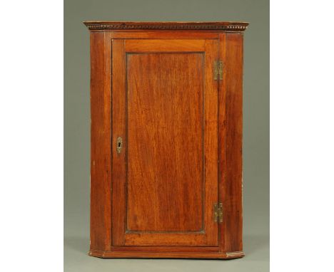 A mahogany wall mounted corner cupboard, late 18th/19th century, having a shaped and dentil moulded frieze, the panel door op