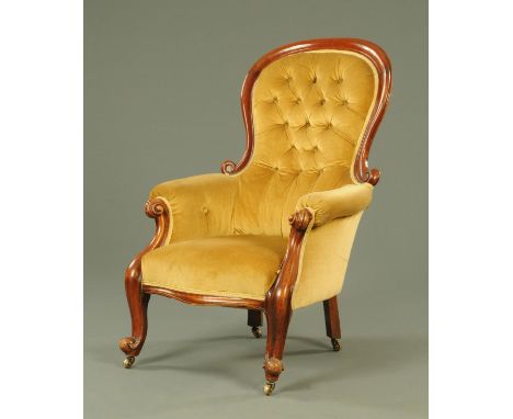 A Victorian mahogany button back armchair, upholstered in gold material with part showframe raised on cabriole legs terminati