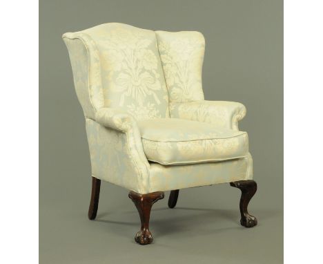A Georgian style wing armchair, late 19th/early 20th century, upholstered in a floral and light blue material and with horseh