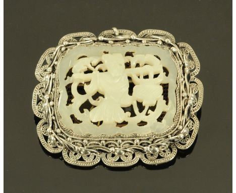 A Chinese carved jade brooch, early 20th century, the jade carved as a child carrying a lantern, mounted in silver filigree w