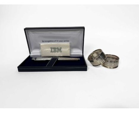 Two hallmarked silver napkin rings, together with a silver mounted ballpoint pen, IBM awarded for 10 years service, in presen