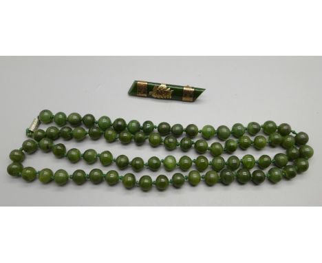 A jade bead necklace and a 9ct gold mounted jade New Zealand fern brooch, a/f 