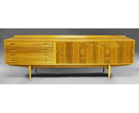 A rectangular teak and hardwood sideboard, attributed to Archie Shine, with four drawers, and two long doors, on tapering cyl