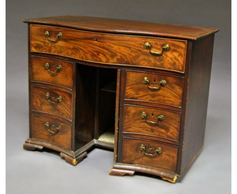 A George III mahogany serpentine knee hole desk, 18th century, the shaped top with one long drawer over three short drawers, 