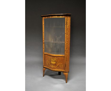 An Edwardian inlaid and painted serpentine corner cupboard, the central convex glass inclosed within satinwood case, overall 