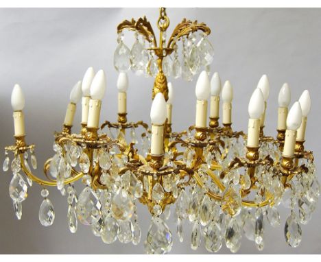 A pair of fifteen light gilt metal and lustre hung chandeliers, the central columns of foliate scrolling form, with scrolling