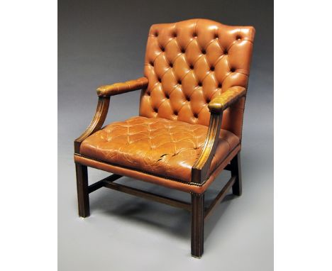 A brown leather button back arm chair, 20th century, raised on fluted square legs. 