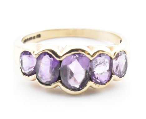 A hallmarked 9ct gold and amethyst five stone ring. The 9ct yellow gold ring set with five graduating half bezel set oval cut