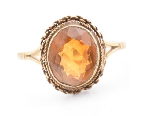A hallmarked 9ct gold and citrine ring. The 9ct yellow gold ring having a bezel set oval cut citrine set in a mount with rope