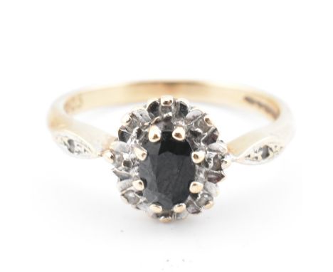 A hallmarked 9ct gold, sapphire and diamond cluster ring. The ring having a central mixed oval cut sapphire surrounded by a h