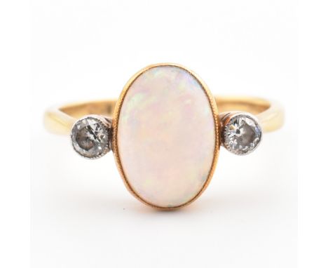 An Edwardian 18ct gold opal and diamond three stone ring. The ring set with an oval cut opal cabochon flanked by two bezel se