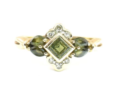 A hallmarked 9ct gold, diamond and green sapphire cluster ring. The ring having a central bezel set green sapphire with six r