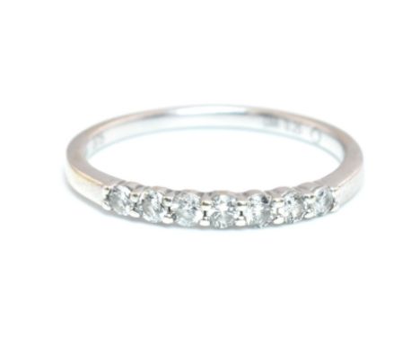 A hallmarked 9ct white gold and diamond half hoop ring. The 9ct white gold half hoop ring set with seven shared claw set roun
