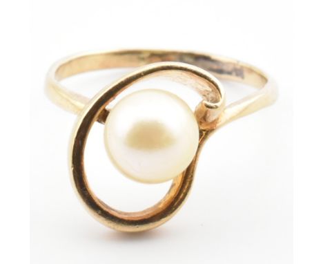 A gold and pearl ring. The ring set with a single round pearl set in a swirl detail mount to polished shank. Unmarked however