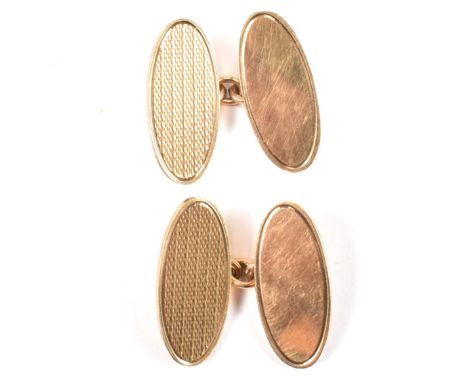 A pair of hallmarked 9ct gold cufflinks. The chain style cufflinks having oval heads with engine turned decoration to cable l