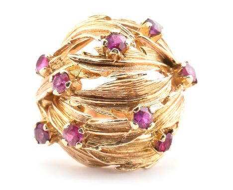 A hallmarked 9ct gold and ruby leaf bombe ring. The hallmarked 9ct yellow gold ring of pierced, overlapping foliate form havi