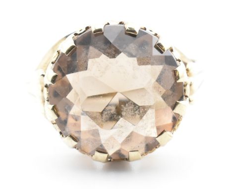 An 8ct gold and smoky quartz ring. The ring having a round cut smoky quartz set in a decorative mount to fluted shoulders. Ma