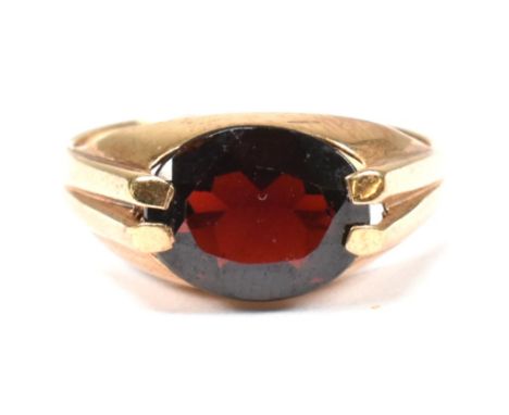 A hallmarked 9ct gold and garnet ring. The 9ct gold ring having a double prong set east-west oval cut garnet to shank. Hallma