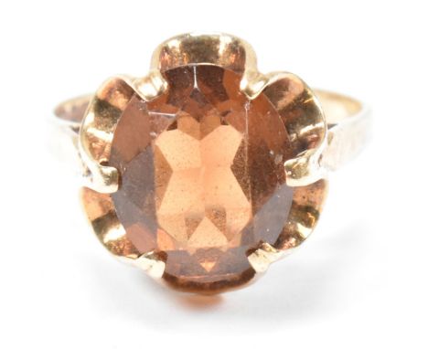 A hallmarked 9ct gold and citrine ring. The ring having with a single oval cut citrine set in a scalloped mount to tapered sh