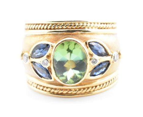 An Etruscan style hallmarked 18ct gold, tourmaline, sapphire and diamond ring. The 18ct gold band ring set with a central bez
