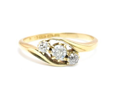 An Edwardian hallmarked 18ct gold and diamond three stone crossover ring. The 18ct yellow gold ring having three graduating r