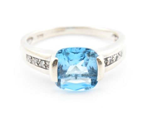 A hallmarked 9ct white gold, topaz and diamond ring. The 9ct white gold ring having a central half bezel set cushion cut topa