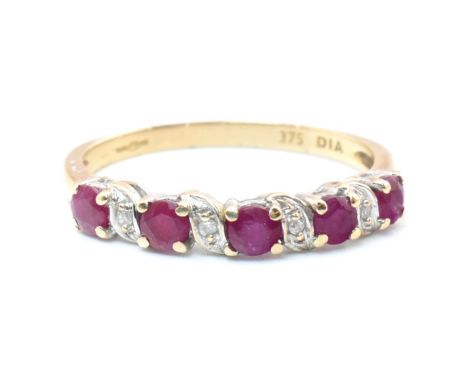 A hallmarked 9ct gold, ruby and diamond half hoop ring. The 9ct yellow gold ring set with five four claw set round cut rubies