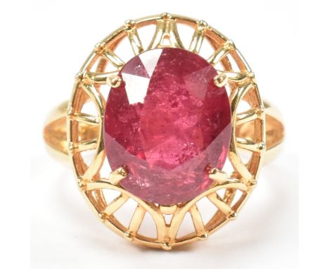 A hallmarked 18ct gold and ruby ring. The ring having a single oval cut ruby set in a decorative, pierced oval mount to bifur