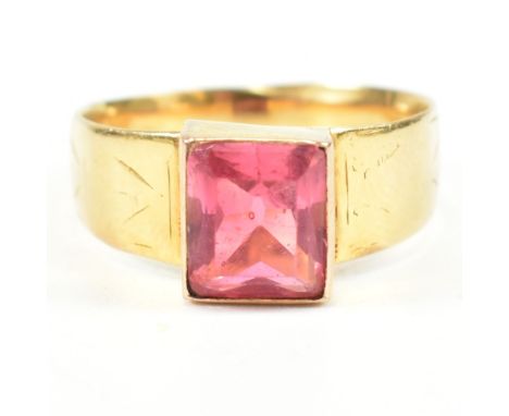 A hallmarked 18ct gold and pink paste ring. The ring set with a single bezel set baguette cut pink paste stone with chevron e