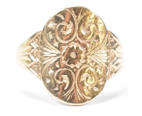 A hallmarked 9ct gold engraved shield ring. The ring having a central oval shaped shield engraved with foliate and scrolling 