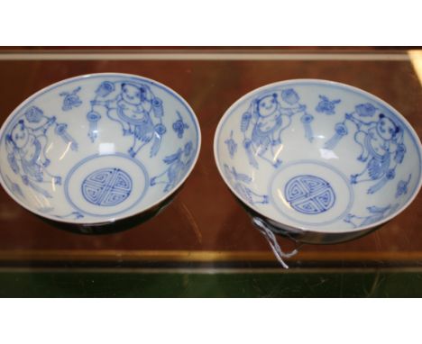 A pair of Chinese blue and white bowls, painted to the centre with four dancing figures, the exteriors with cafe-au-lait glaz