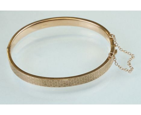 9ct rose gold hinged bangle, engraved textured design to upper half, the tongue and box clasp with safety chain 